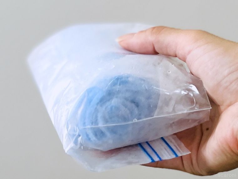 ジップ付きのポリ袋に入った冷凍おしぼりを手で持っている様子
