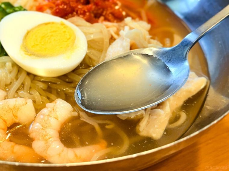 「海老と蒸し鶏のコク旨冷麺」のスープをスプーンですくっている様子