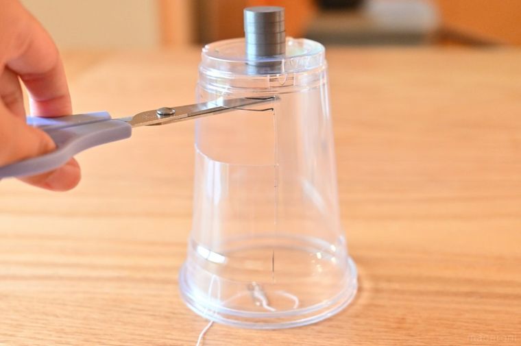 磁石がついたカップとはさみとテーブルに落ちたクリップ