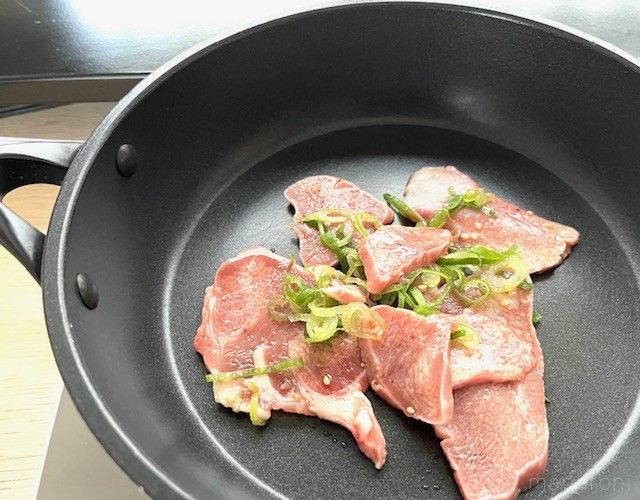 フライパンで味付けされた豚肉のタンを焼いている