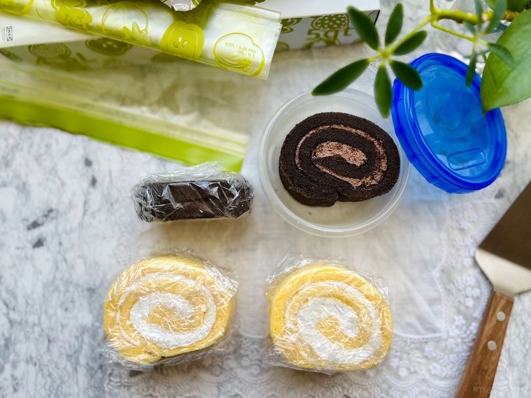 ラップで包んだコストコの米粉のスイスロール、ジップ付き保存袋、青い蓋の保存容器