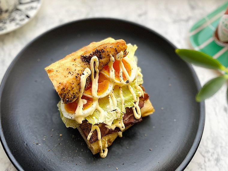 コストコのベーコンバトンにレタスとゆで卵を挟んで作ったサンドイッチを黒いプレートにのせたところ