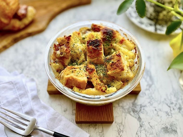 クロス型のトリベットに置いたコストコのベーコンバトンを使って作ったパングラタン、白いナプキン、フォーク