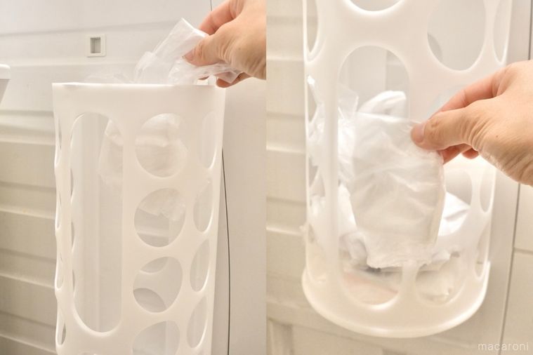 丸い穴が開いた白いプラスチック製の袋ディスペンサーにビニール袋を入れて引き出す様子