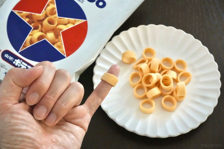白い皿とトリコロールカラーのパッケージと小指にポテトスナックをはめる様子