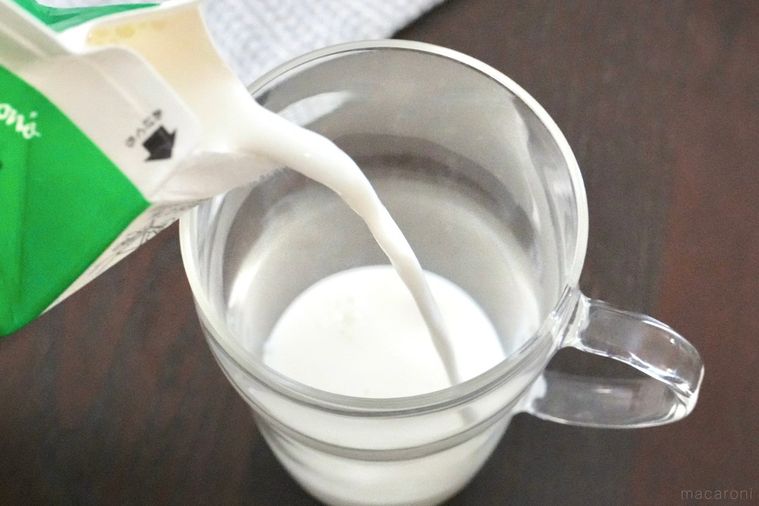 取手付きのグラスに緑色の牛乳パックから牛乳を注ぐ様子
