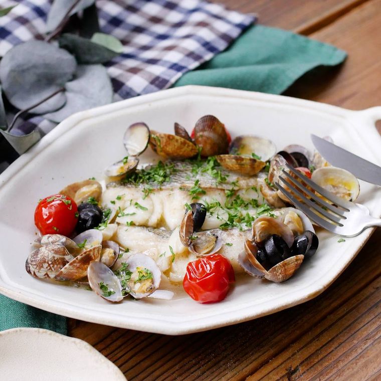 白い皿に盛り付けられたたらのアクアパッツァ