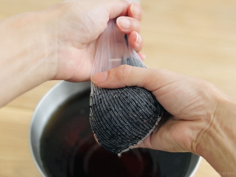 ひじきが入った水きりネットを絞っている様子