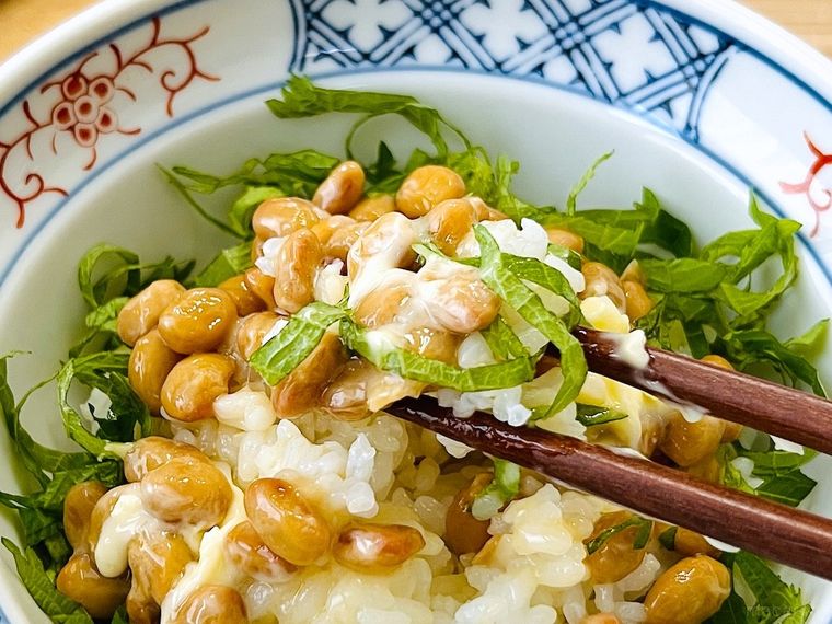 納豆、大葉、バターがのったごはんを箸で持ち上げている様子
