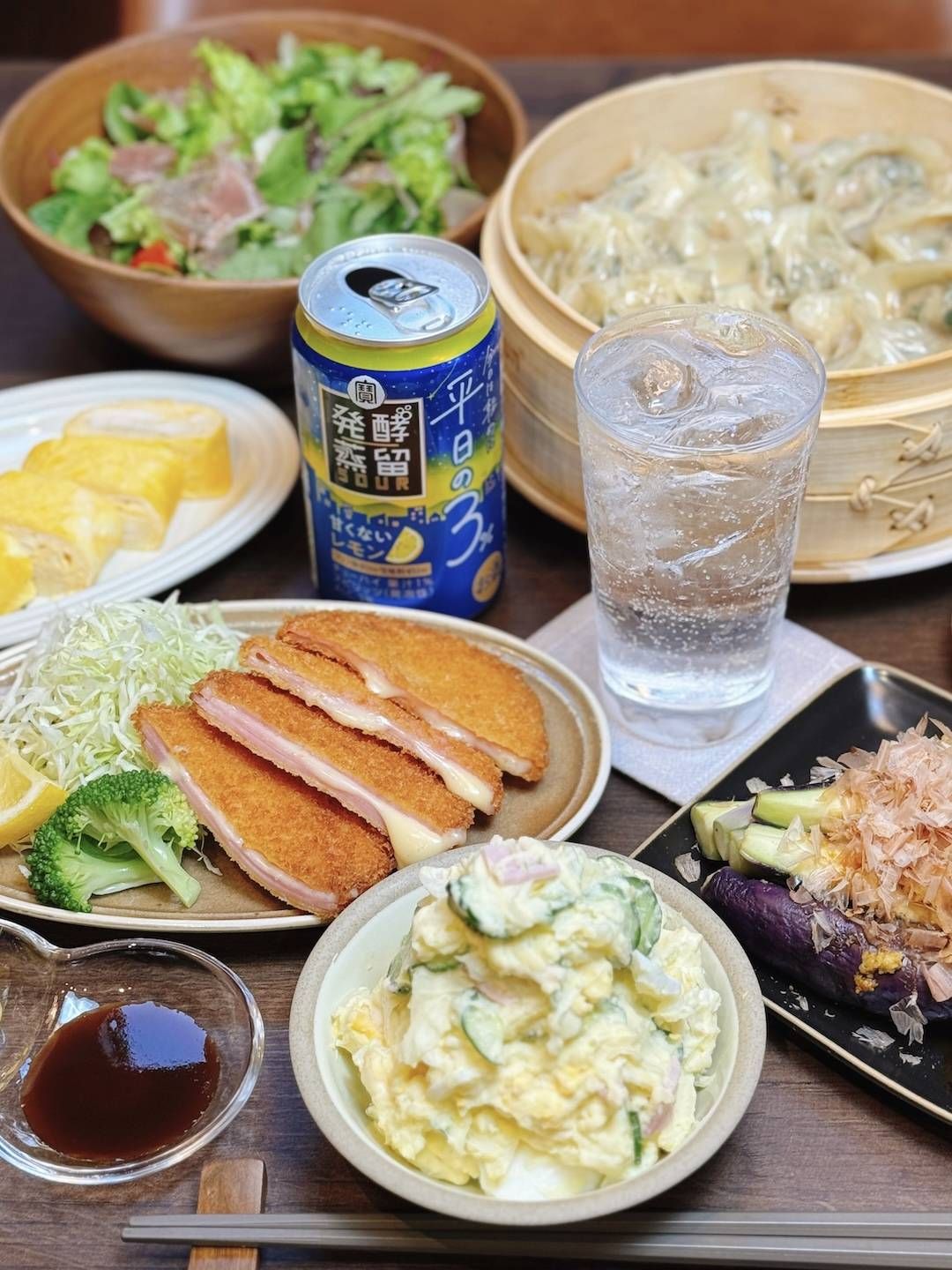 発酵蒸留サワー平日の３とともに揚げ物やポテトサラダ、蒸し餃子などがぎっしりと並ぶ食卓。