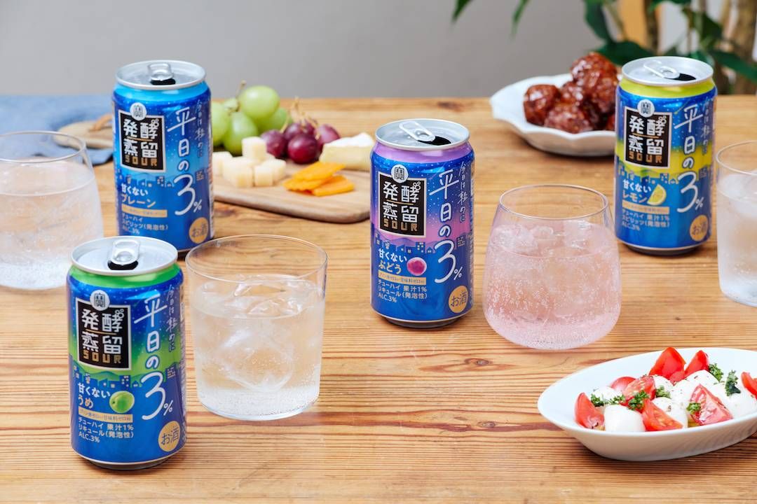 テーブルの上に料理と発酵蒸留サワー 平日の３4種類 プレーン・レモン・ぶどう・うめの缶が並んでいる様