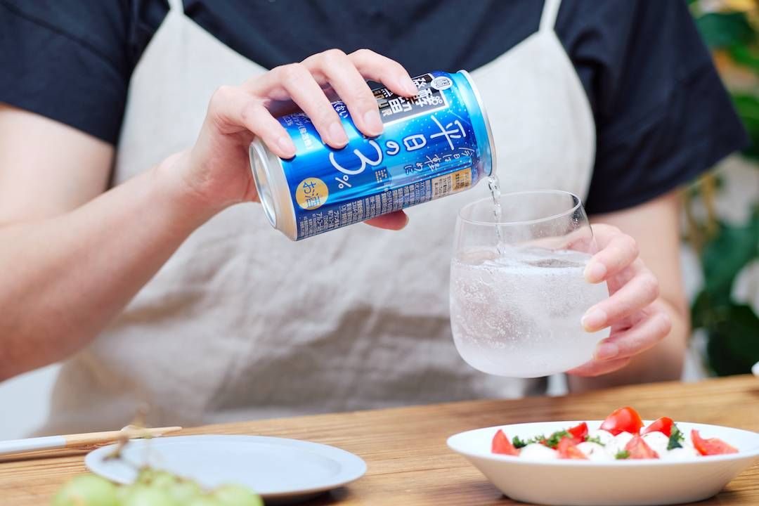 食卓でグラスに発酵蒸留サワー平日の３を注いでいる女性の手元