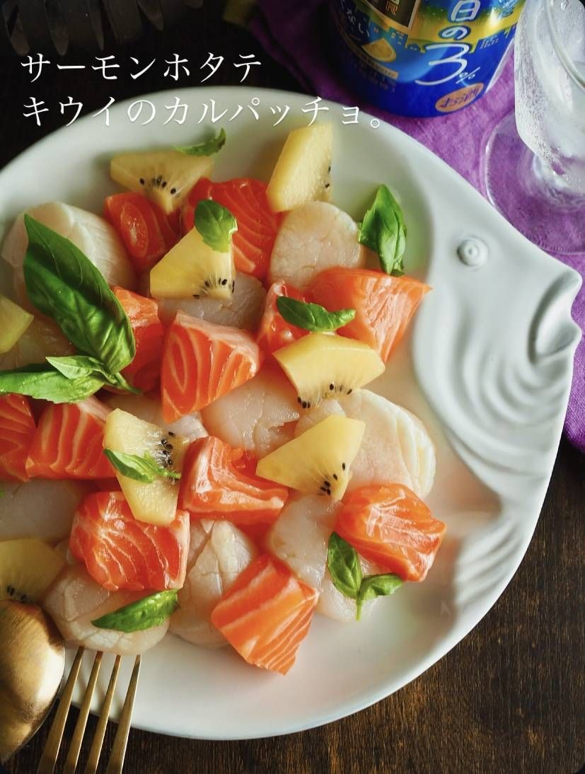 白い大皿に盛られたサーモン、キウイ、ホタテのカルパッチョ