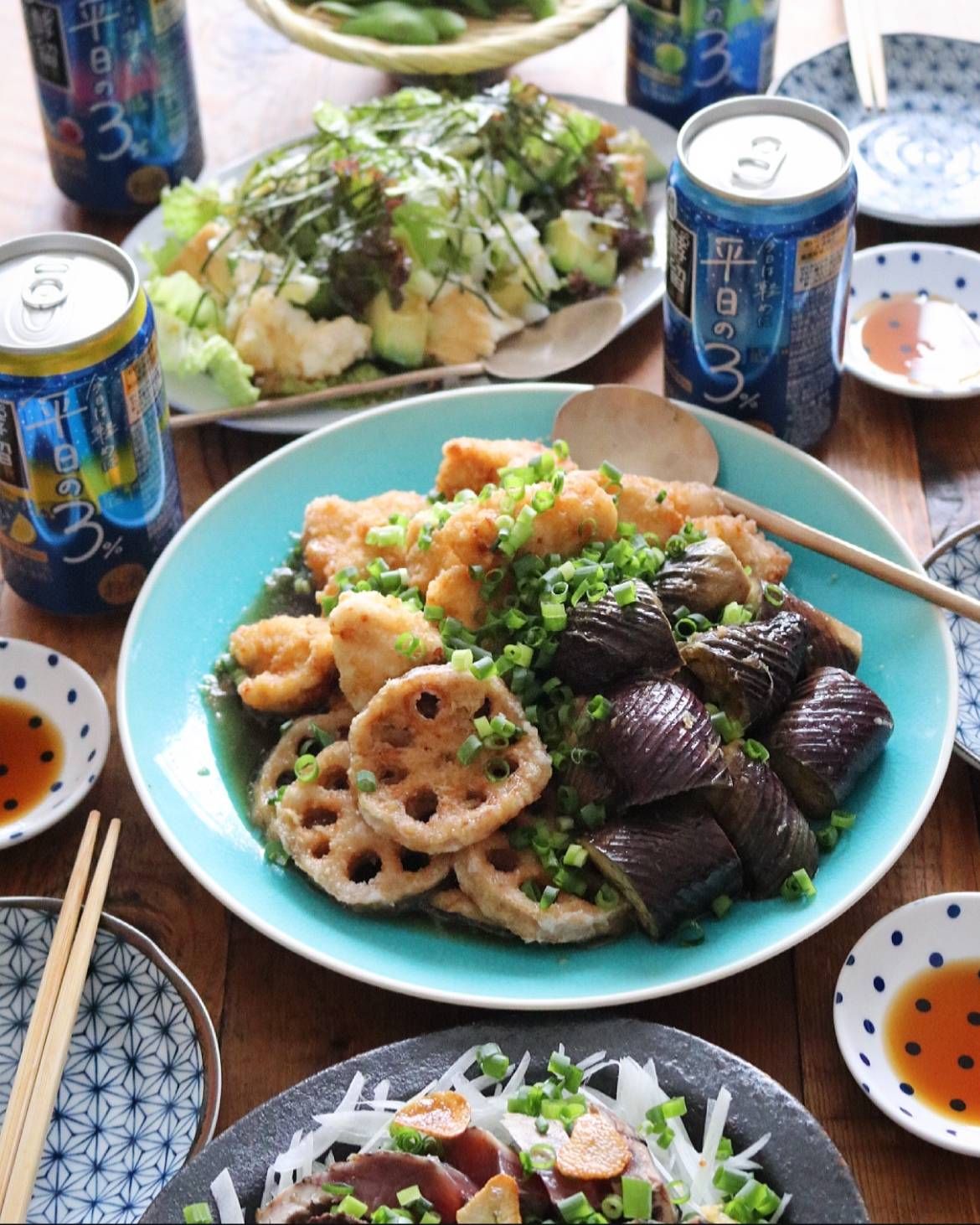 発酵蒸留サワー平日の３と、大皿に盛られた茄子と蓮根の揚げ浸し、取り皿がセッティングされたテーブル。