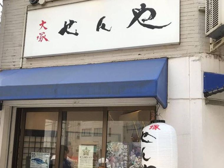 白い看板と青い日よけがついている大塚せんやの外観