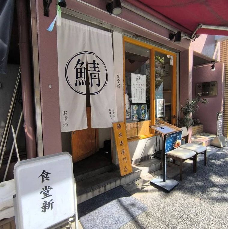 店名入りの白いのれんがかかった鯖黒煮専門店 食堂新 神保町の外観