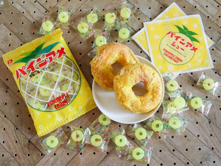 パインアメが散らばった板の上にパインアメシューと包み紙、パインアメの袋が置かれている