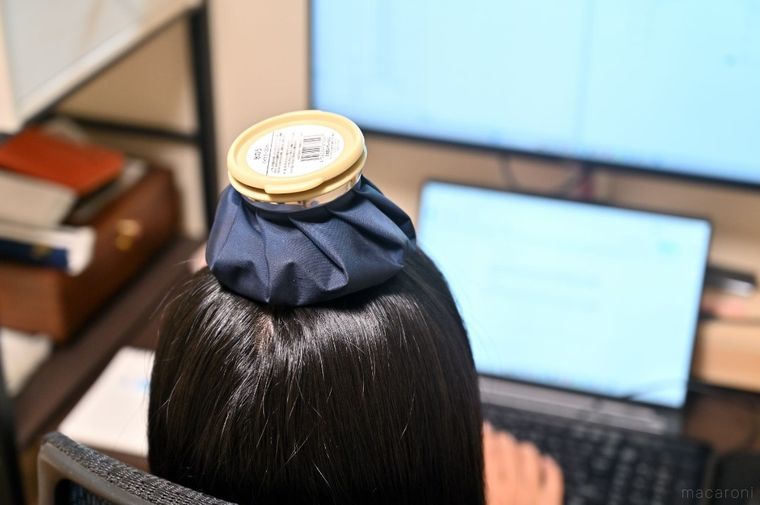 氷のうを頭にのせて仕事している女性