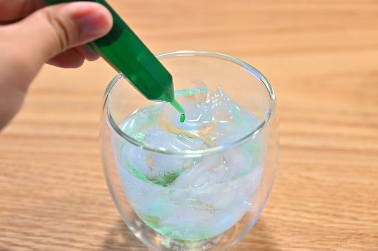 炭酸水にメロンのシロップを入れている様子