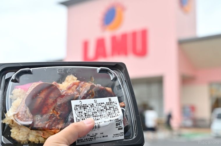 ラ・ムーの外観を背景に、うな重を手に持っている