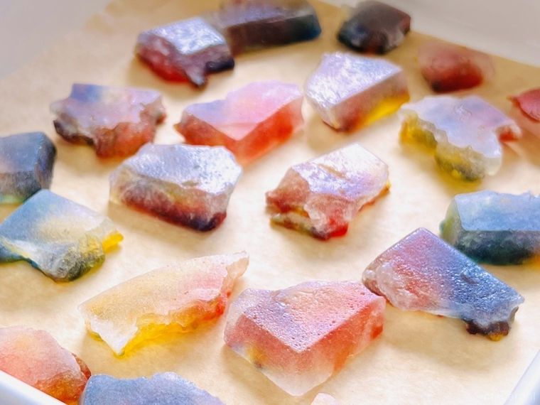 宝石のような形をしたマーブル模様の琥珀糖がバットの上に並んでいる様子