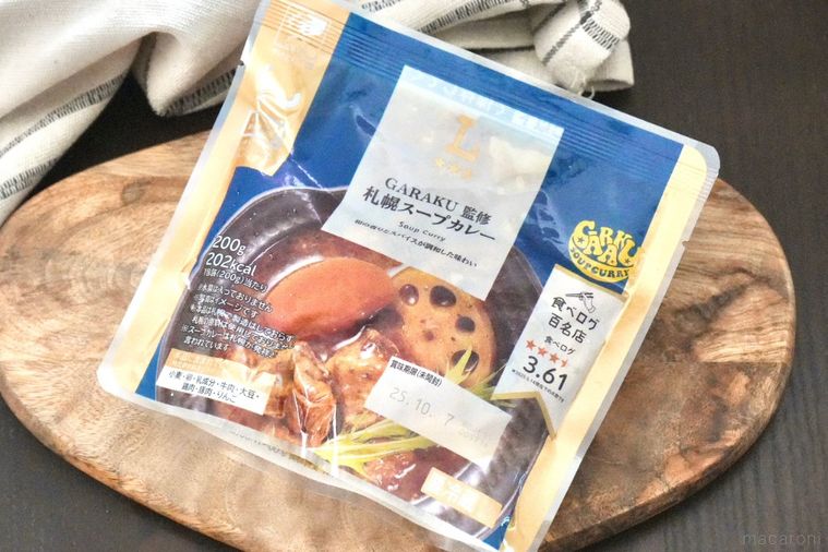 木のカッティングボードにのった青色と金色のパッケージのレトルトスープカレーと生成色の布