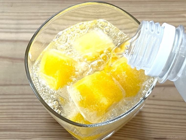マンゴーのフルーツ氷が入ったグラスに炭酸水をそそいでいる様子