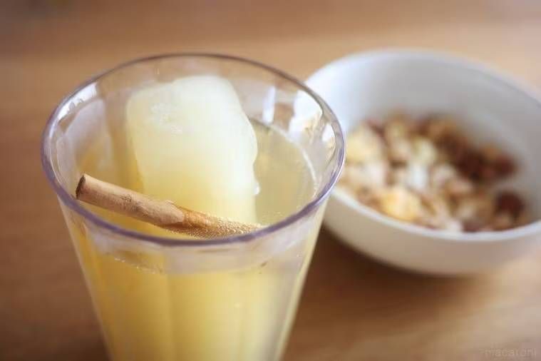 りんごジュース氷と炭酸水が入ったグラスにシナモンスティックを浮かべた様子