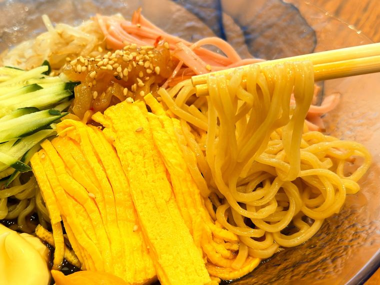 五目冷やし中華の麺を箸で持っている様子