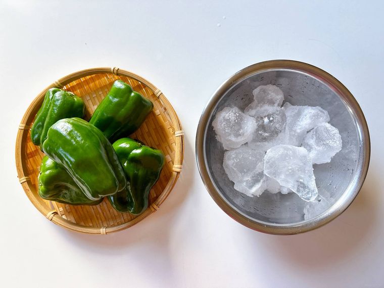 ザルに盛られたピーマン、ボウルに入った氷