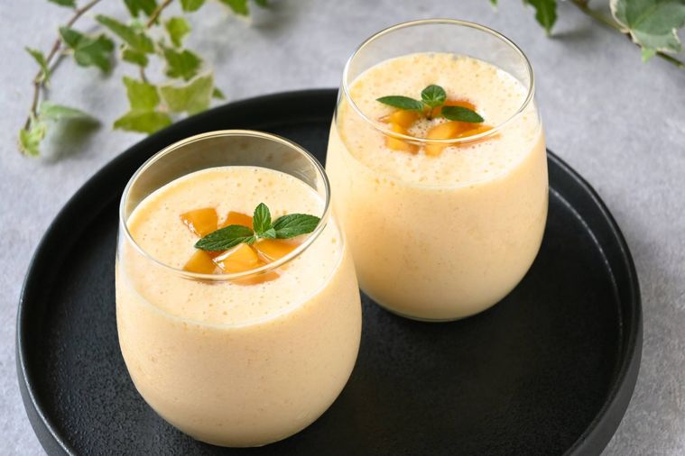 黒い丸型プレートの上にマンゴーラッシーが注がれたグラスが2個並んでいる