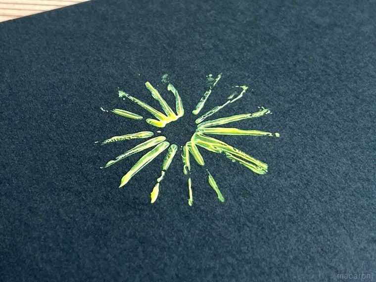 黒い画用紙に黄色い絵の具で花火を描いた様子