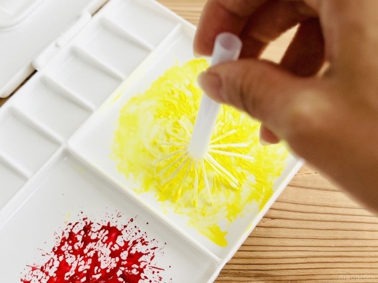 ストローで作ったスタンプに黄色い絵の具をつけている様子