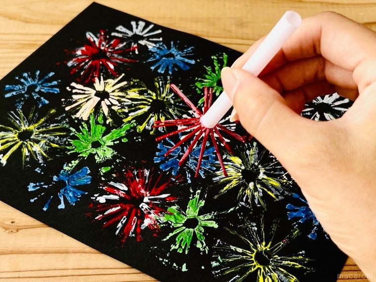 ストローで作ったスタンプで花火の絵を描いている様子