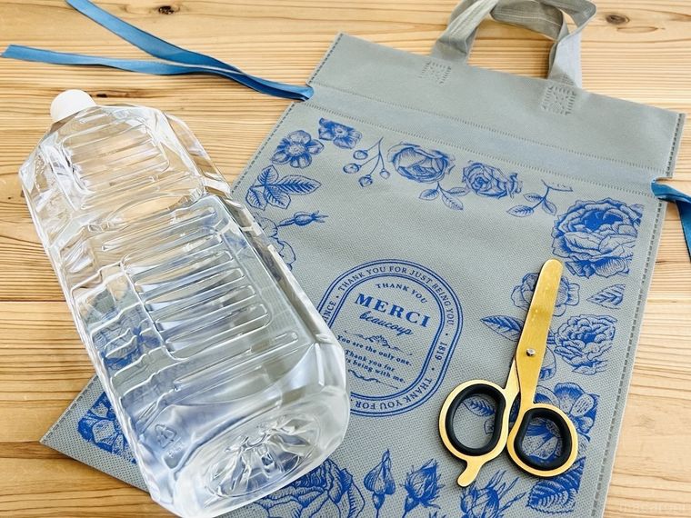 テーブルの上に水が入ったペットボトル、不織布の袋、ハサミが置かれている様子