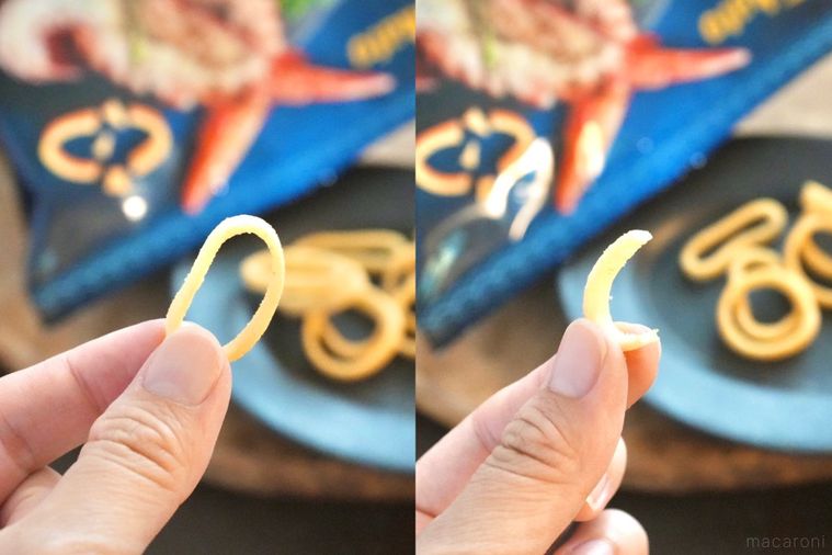 木のカッティングボードにのった黒い小皿にのったポテトリングスナックを手に持って食べる様子