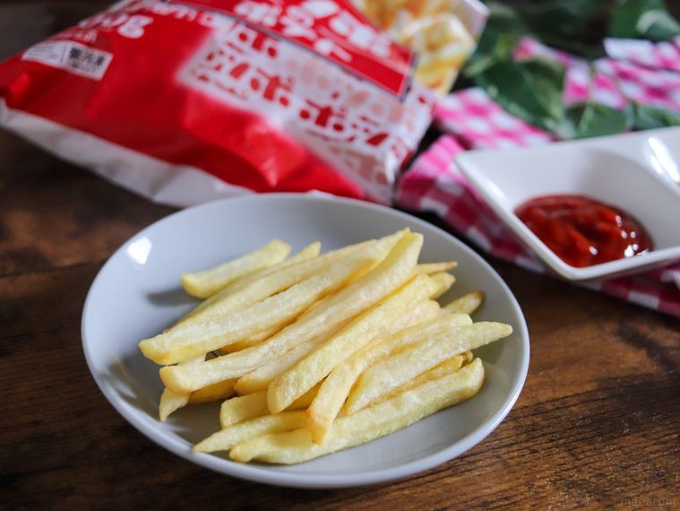 木製のテーブルの上に、ポッポのポテトの外装とお皿に盛り付けられたフライドポテト、ケチャップが置かれている