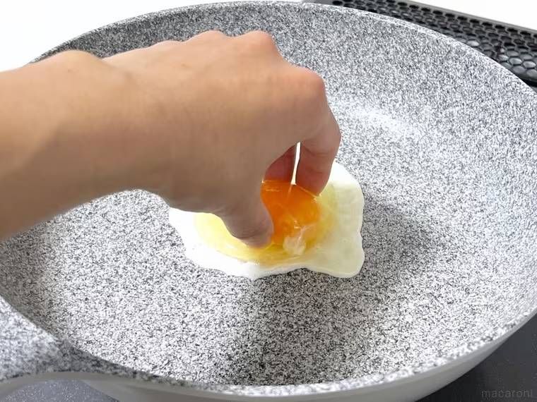 目玉焼きの黄身を手で押さえている様子