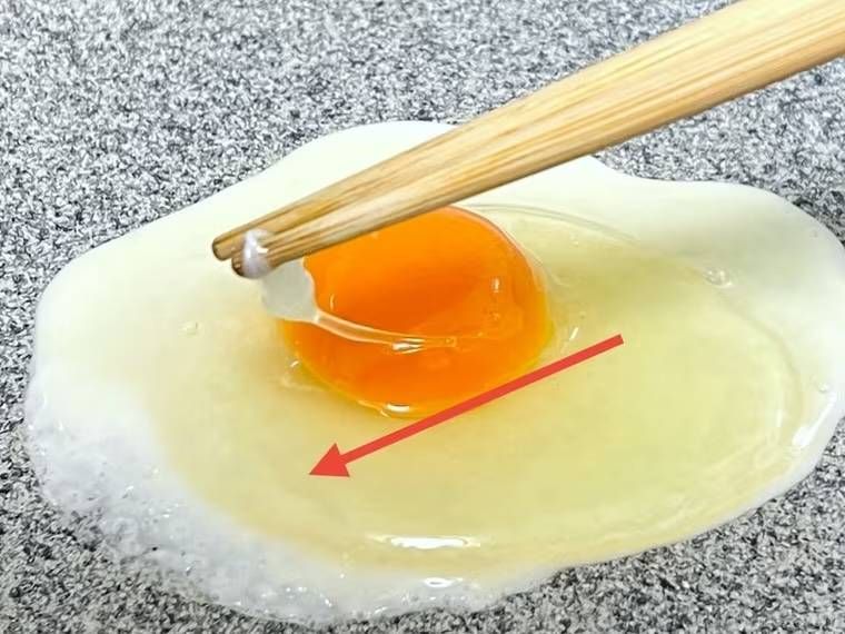 目玉焼きの黄身にかぶさった白身を剥がしている様子