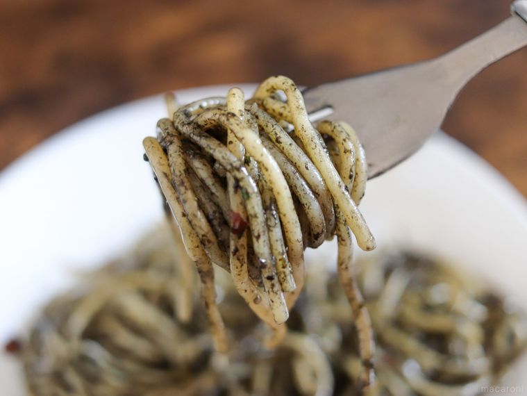 フォークに巻いたイカスミオイルパスタのパスタを持ち上げている様子