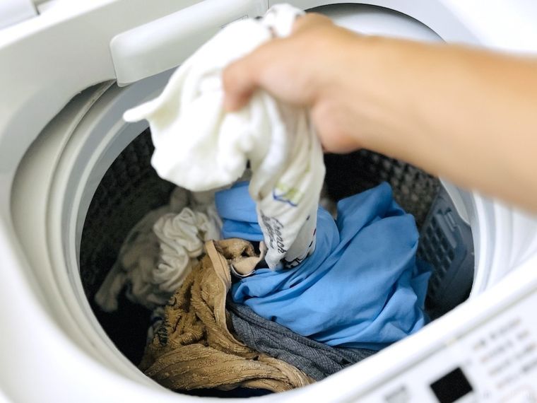 洗濯機からバスタオルを引っ張り出している様子