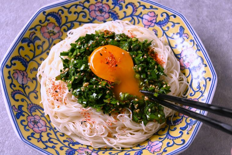 ニラだれそうめんのトッピングの卵黄に箸を差し入れる様子