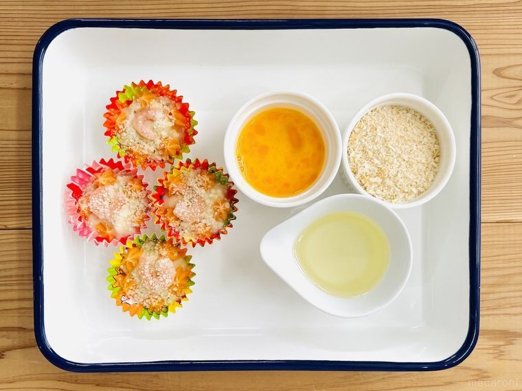 バットの上に冷凍グラタン、溶き卵、パン粉、サラダ油が置かれている様子