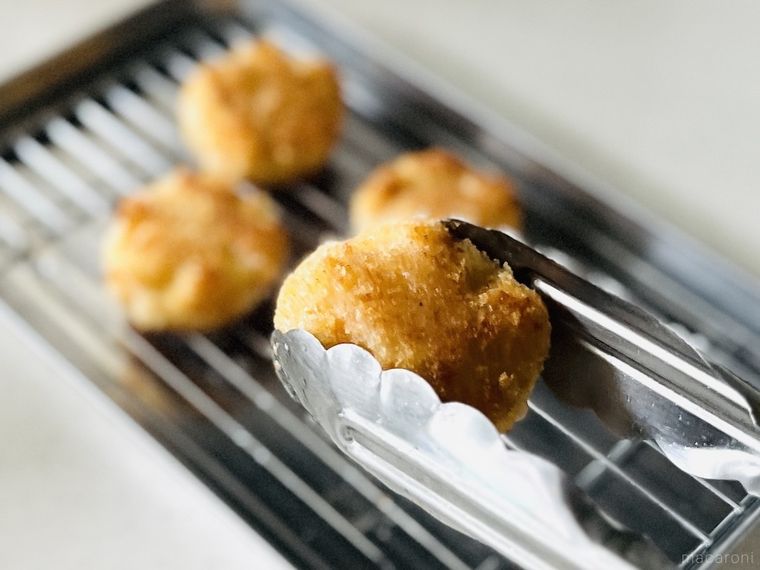 クリームコロッケをトングで持ち上げている様子