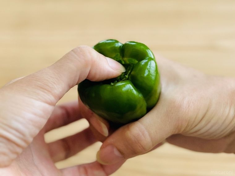 ピーマンのヘタを指で中に押し込んでいる様子