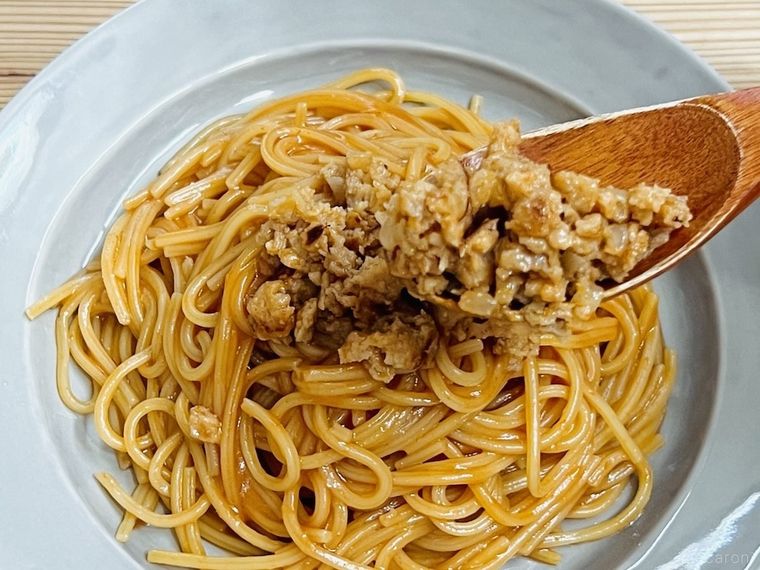 パスタの上に潰したハンバーグをのせている様子