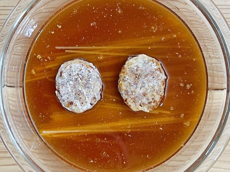 耐熱容器に調味料、水、パスタ、冷凍ハンバーグを入れた様子