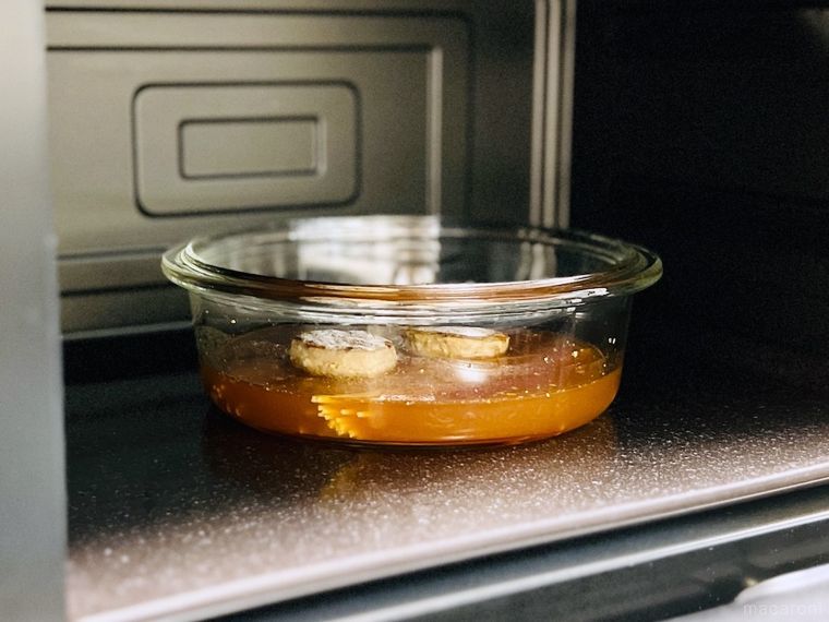 調味料、水、パスタ、冷凍ハンバーグが入った耐熱容器を電子レンジに入れた様子