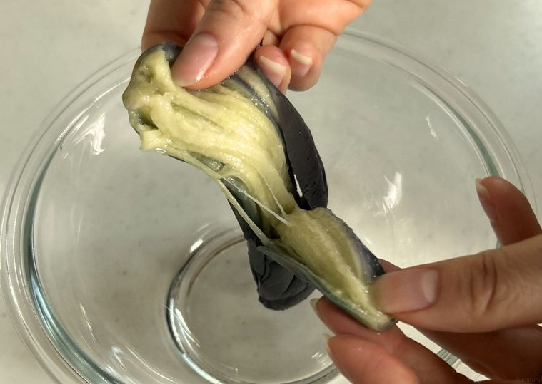 ガラス製のボウルの上で縦に割かれたなす