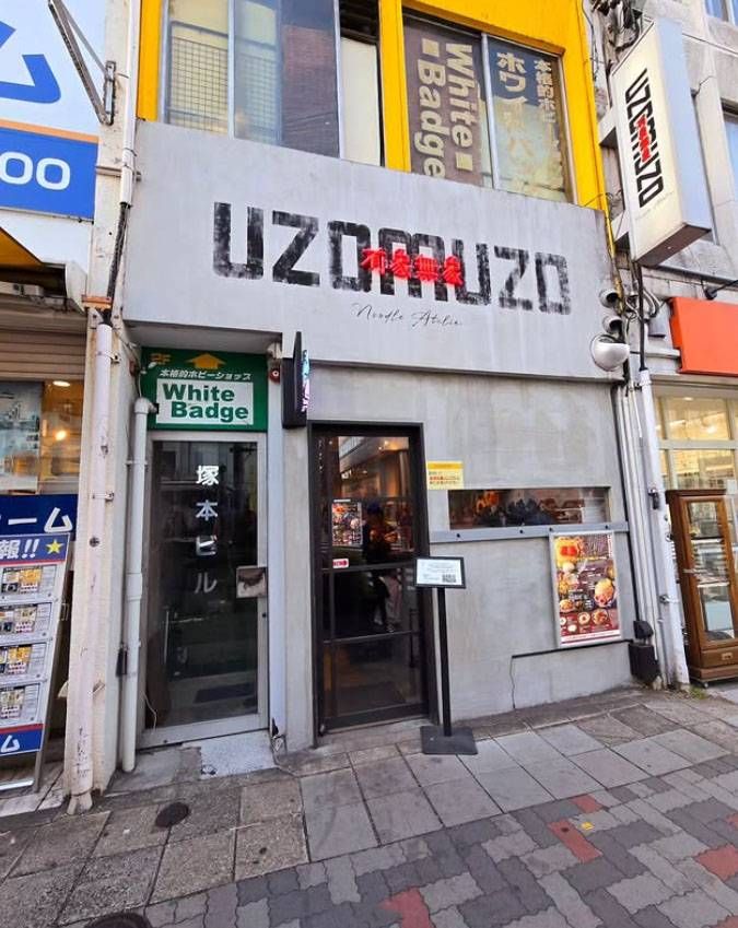 コンクリート調の外壁と看板が掲げられたNoodle Atelier 有象無象uzomuzoの外観